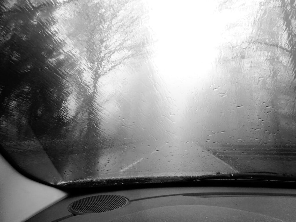 View through a fogged windshield showing reduced driving visibility